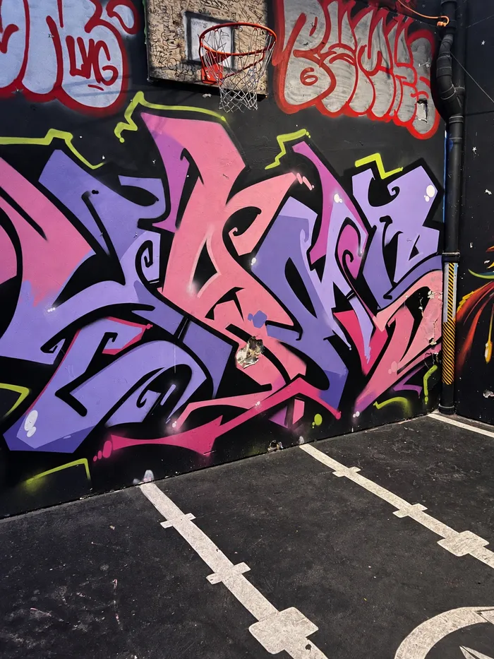 Grafiti en rosa y violeta debajo de un aro de baloncesto