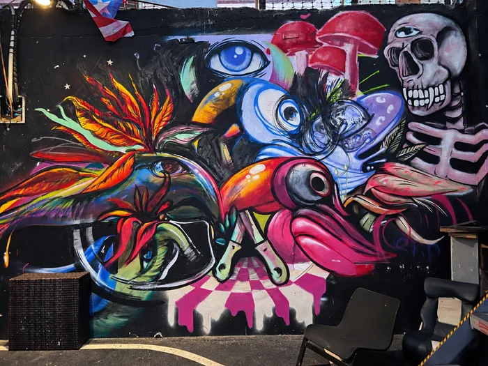 Mural de un tucán, aves del paraíso, hongos y una calavera