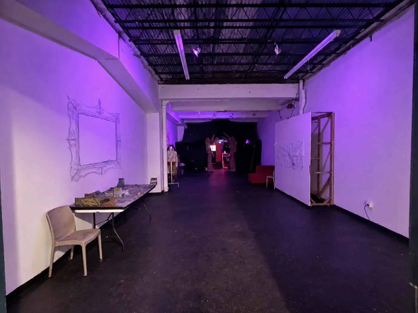 La sala de exhibición: paredes blancas bajo luz violeta y un marco dibujado en la pared