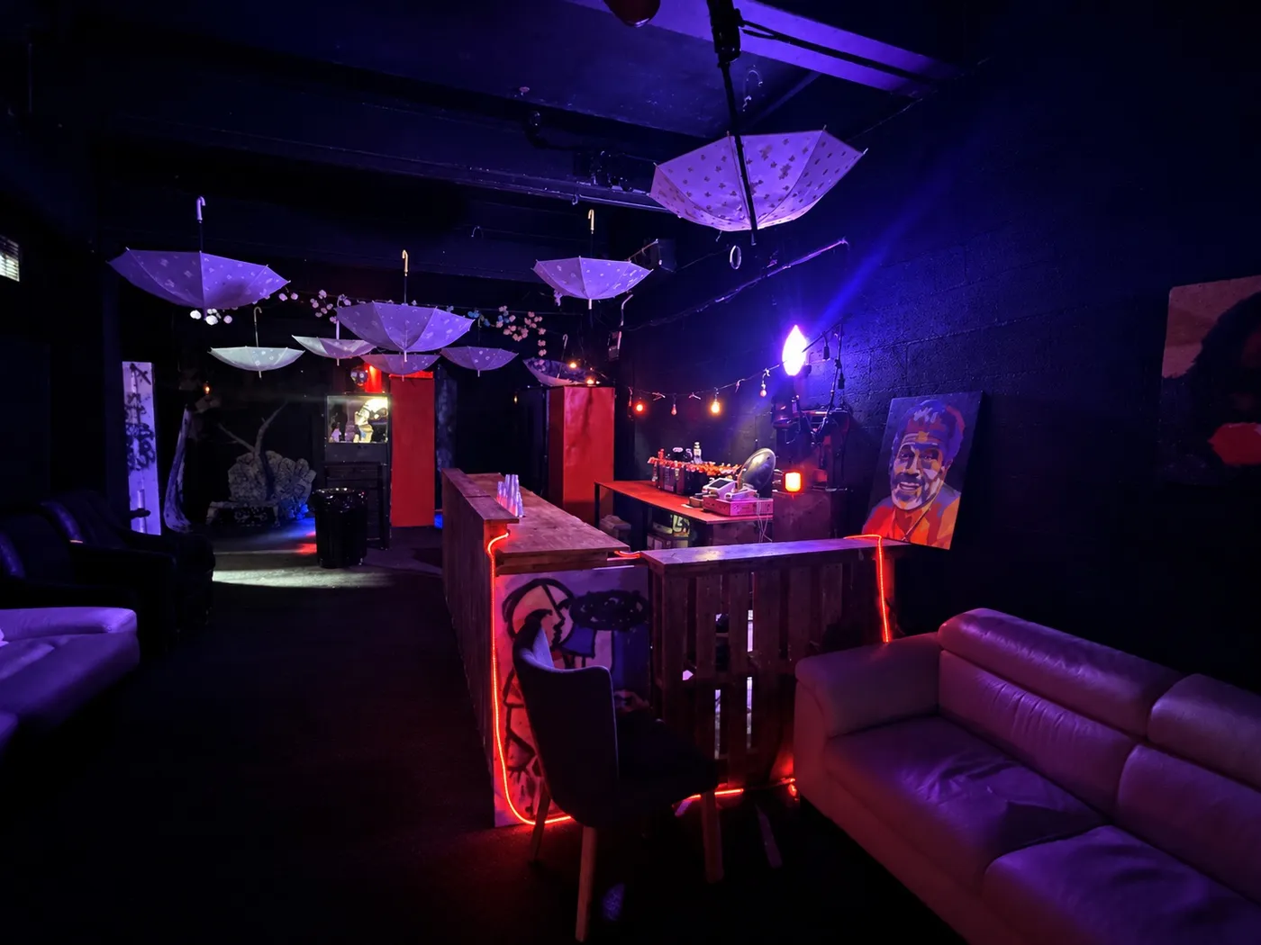 La segunda barra, de madera con luces rojas, bajo sombrillas colgadas del techo