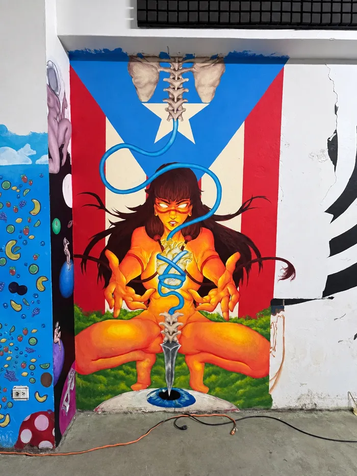 Mural de una figura en naranja frente a la bandera de Puerto Rico