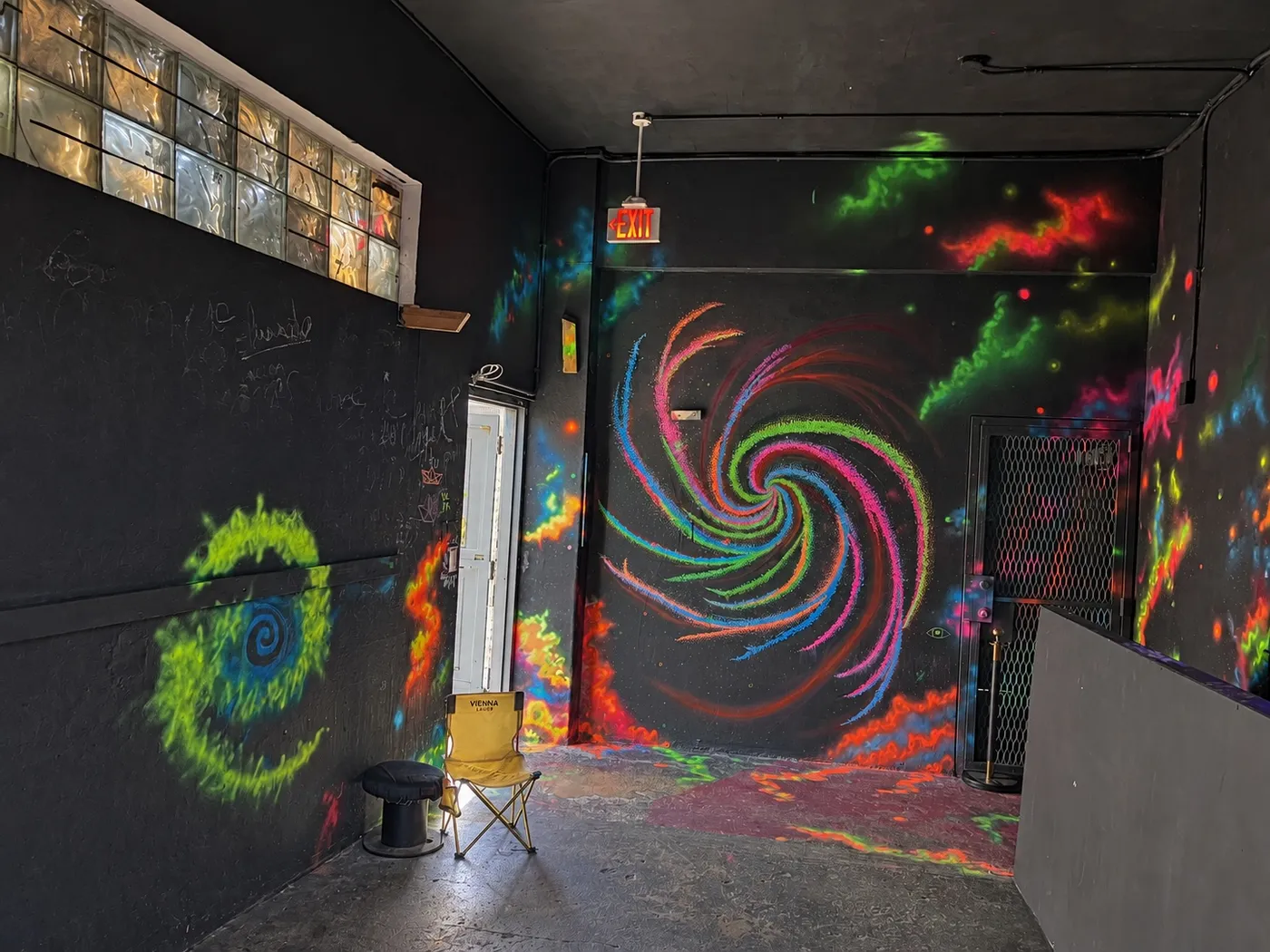 La entrada, con un remolino de colores fluorescentes pintado en la pared negra