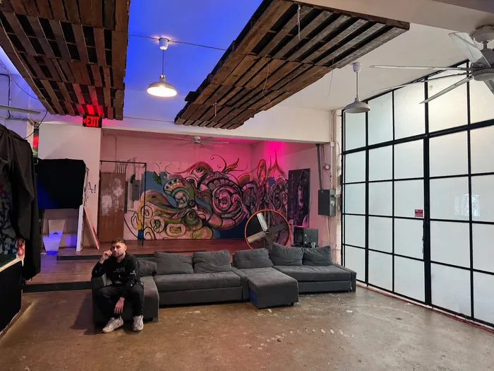 Sala con un sofá en L, ventanales y un mural al fondo