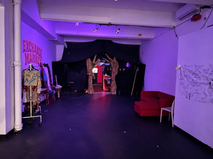 Sala de exhibición con ropa en percheros para un mercado de intercambio y un sofá rojo