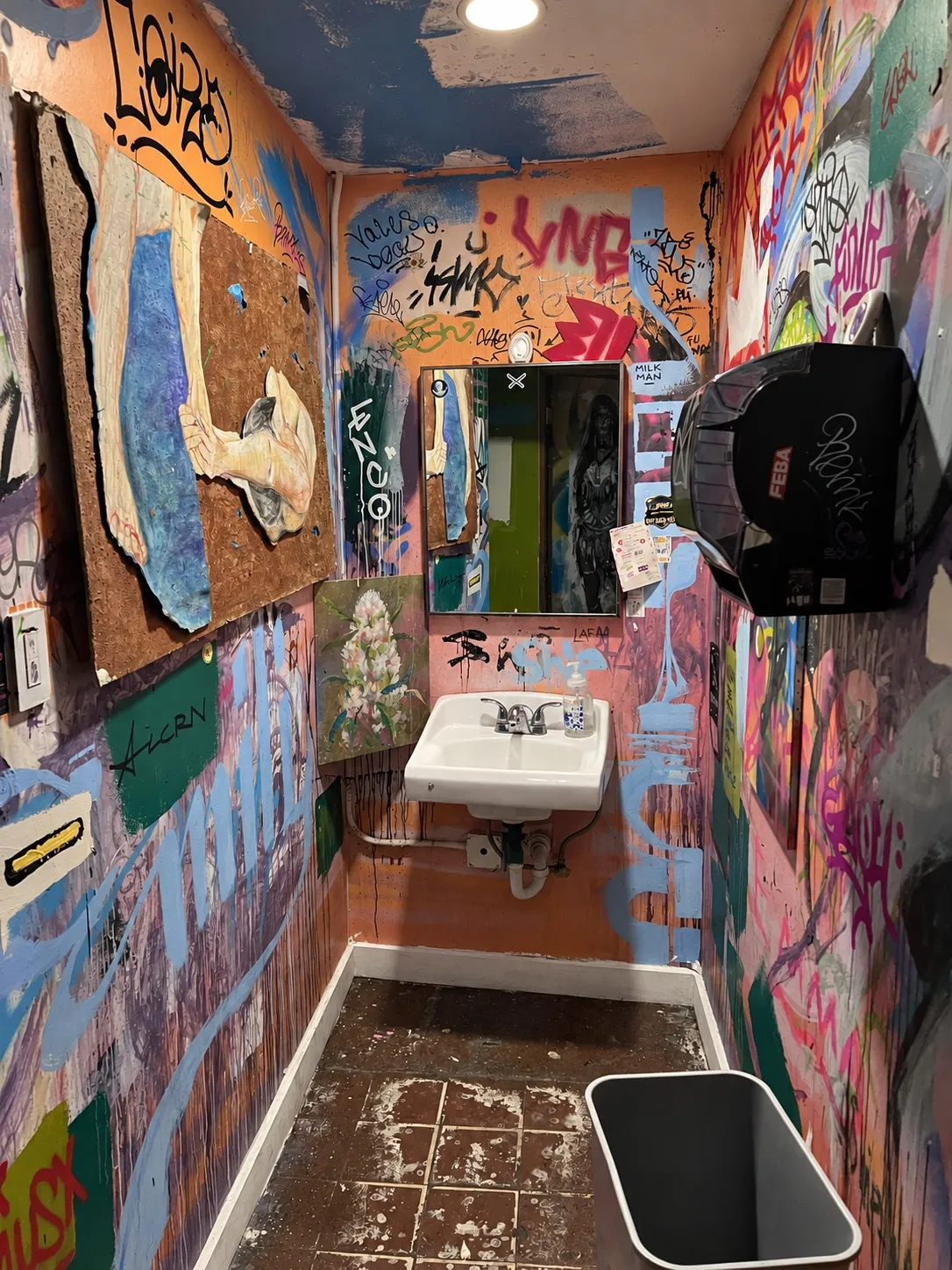 Baño con paredes cubiertas de grafitis y un lavamanos