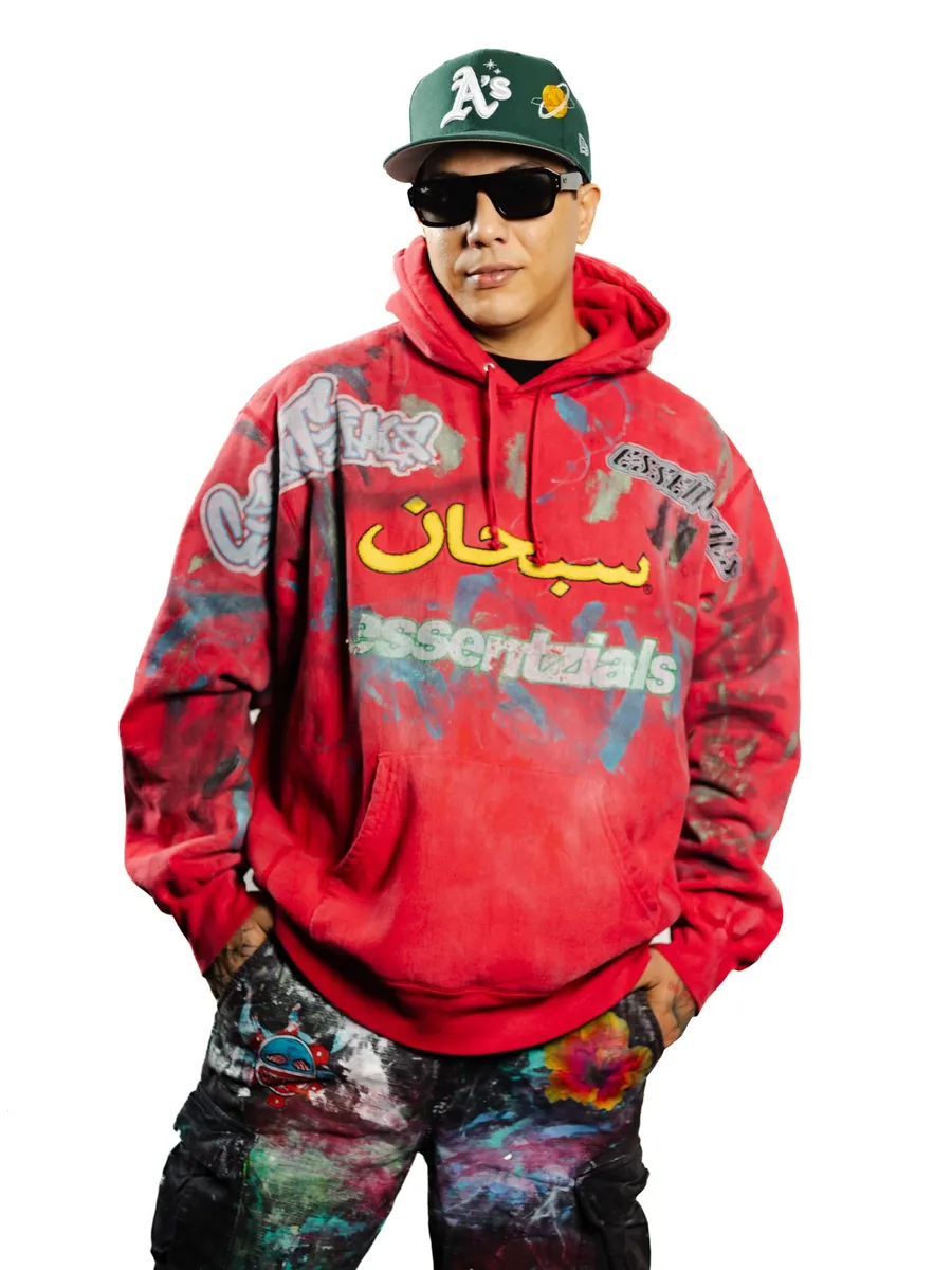 Retrato de Pax Kotto con gorra verde, gafas oscuras y una sudadera roja pintada