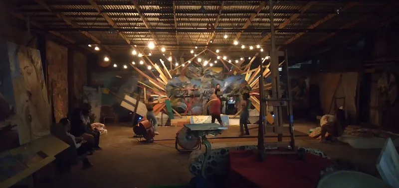 Shipwreck Studios por dentro: murales y pinturas alrededor del escenario, bajo luces colgantes, durante una presentación.